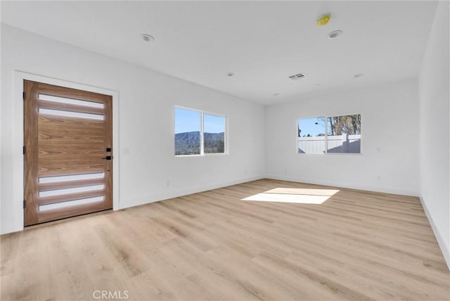 spare room featuring baseboards, visible vents, and light wood-style floors