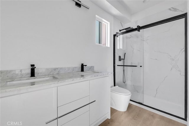 bathroom with a marble finish shower, wood finished floors, a sink, and toilet