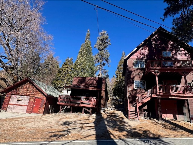 view of front of property with a wooden deck, an outbuilding, and a garage