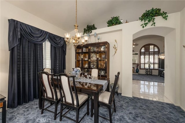 carpeted dining area featuring arched walkways and an inviting chandelier