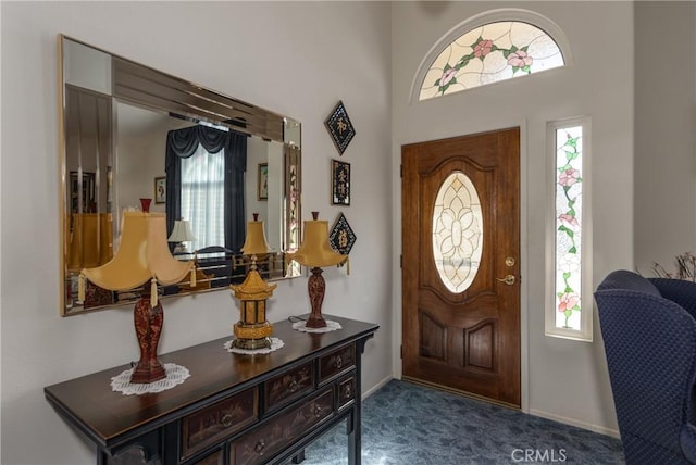 entryway with plenty of natural light, baseboards, and dark carpet