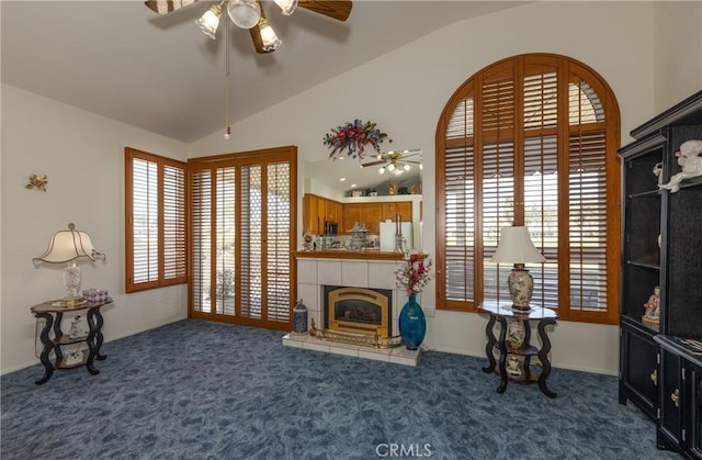 carpeted living area featuring a ceiling fan, vaulted ceiling, a healthy amount of sunlight, and a tile fireplace