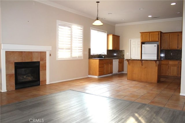 kitchen featuring a center island, light tile patterned floors, white appliances, and ornamental molding