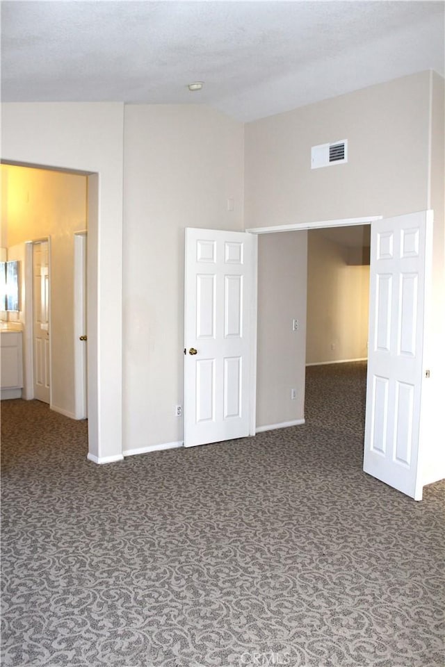 carpeted spare room featuring vaulted ceiling