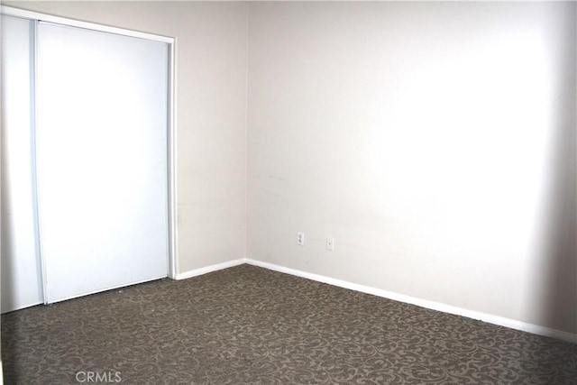 unfurnished room featuring dark carpet