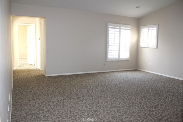 carpeted empty room featuring vaulted ceiling