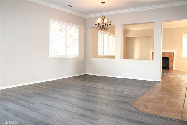 spare room with dark hardwood / wood-style flooring, crown molding, a fireplace, and a notable chandelier