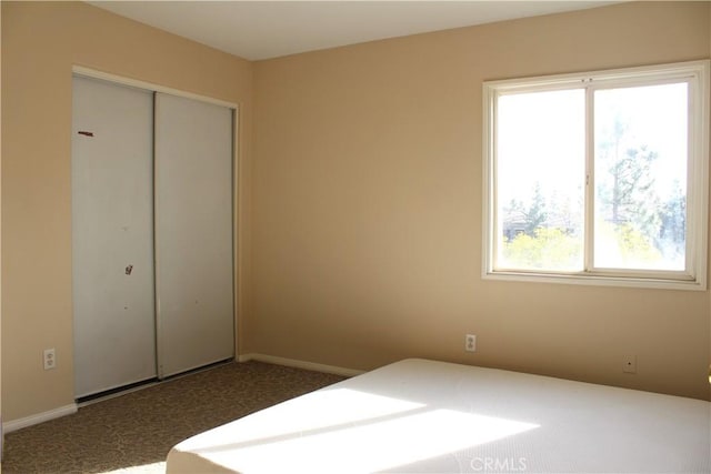 unfurnished bedroom with dark carpet and a closet