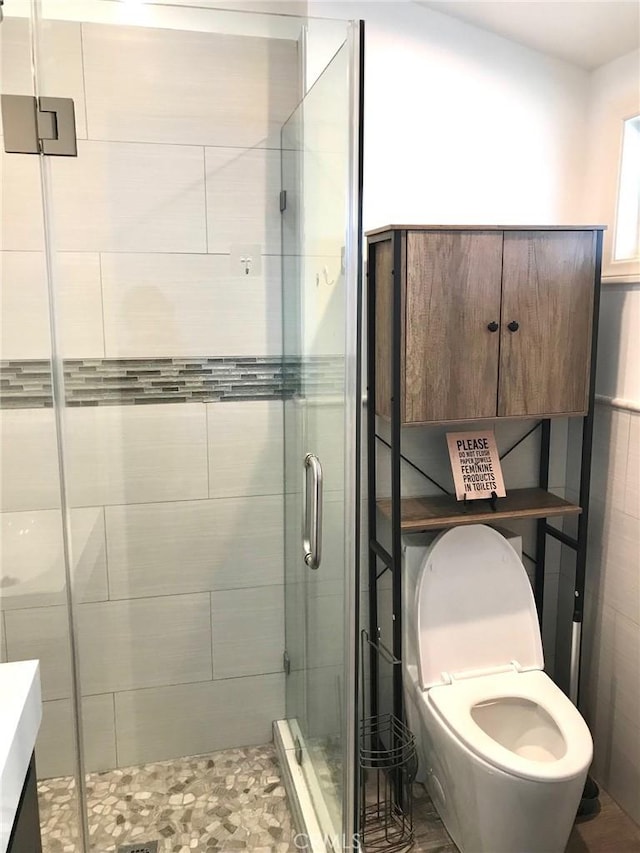 bathroom featuring vanity, toilet, and a shower with door