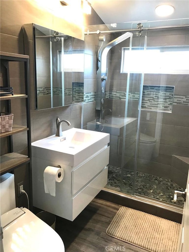 bathroom with toilet, vanity, a shower with shower door, and hardwood / wood-style flooring