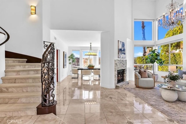 entrance foyer featuring a notable chandelier, a towering ceiling, a fireplace, and a wealth of natural light