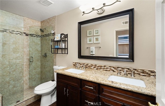 bathroom featuring a shower with door, vanity, tasteful backsplash, and toilet