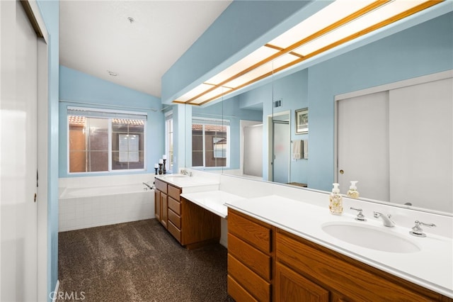 bathroom with a relaxing tiled tub, vaulted ceiling, and vanity