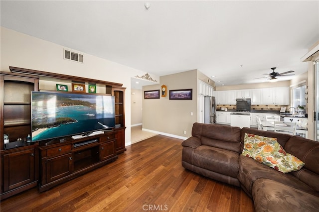 living room with dark wood-type flooring, ceiling fan, and sink