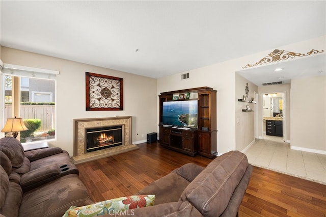 living room with a tile fireplace and hardwood / wood-style floors