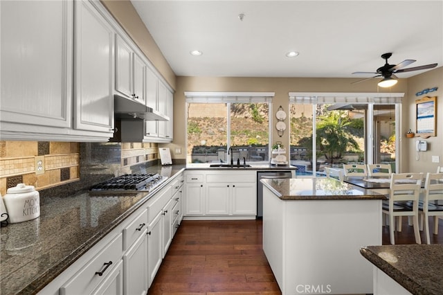 kitchen with stainless steel appliances, sink, white cabinetry, dark stone countertops, and dark wood-type flooring