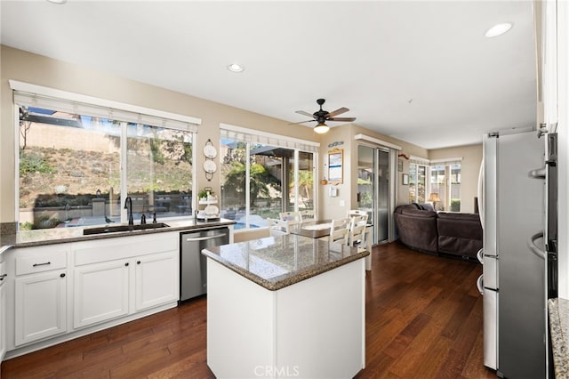 kitchen with appliances with stainless steel finishes, ceiling fan, dark stone counters, white cabinets, and sink