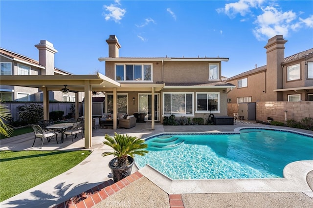 back of property featuring ceiling fan, a fenced in pool, and a patio