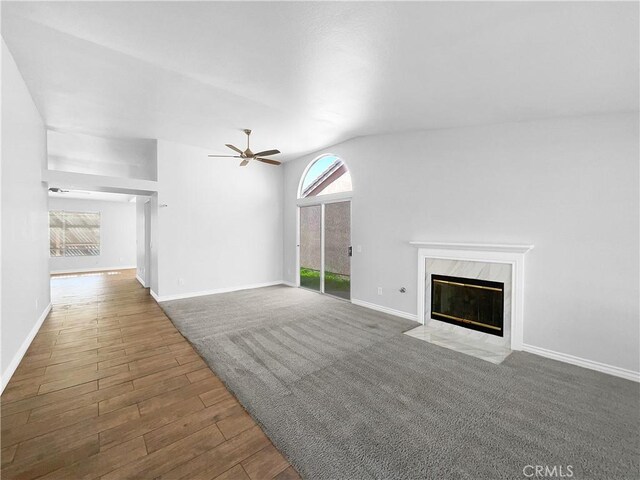 unfurnished living room featuring dark wood-type flooring, ceiling fan, lofted ceiling, and a fireplace