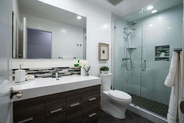 bathroom featuring vanity, a shower with shower door, tasteful backsplash, and toilet