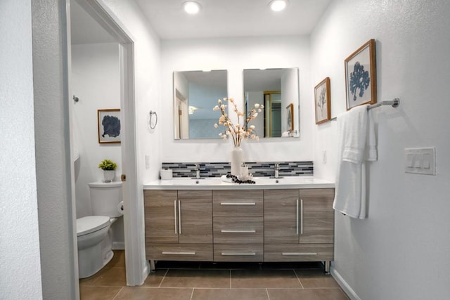 bathroom featuring toilet, tile patterned flooring, decorative backsplash, and vanity