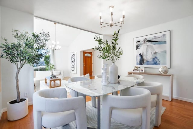 dining room featuring an inviting chandelier, vaulted ceiling, and light hardwood / wood-style flooring