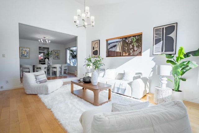 living room featuring a high ceiling, a notable chandelier, and light hardwood / wood-style flooring