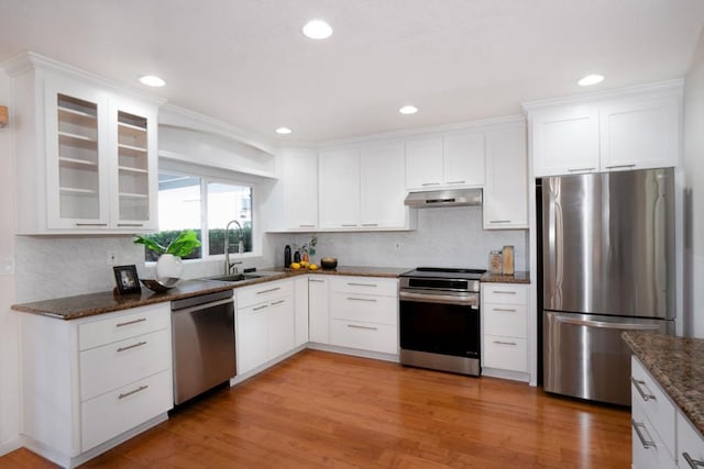 kitchen with appliances with stainless steel finishes, white cabinets, dark stone countertops, and sink