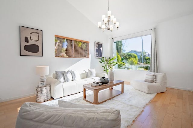 living room with a notable chandelier, light hardwood / wood-style floors, and high vaulted ceiling