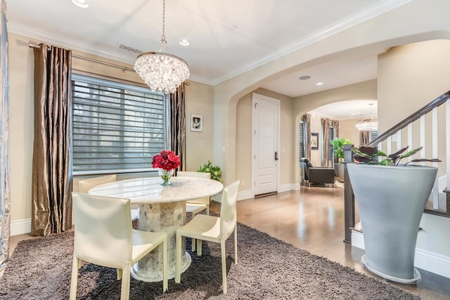 dining space featuring a chandelier, wood-type flooring, and crown molding