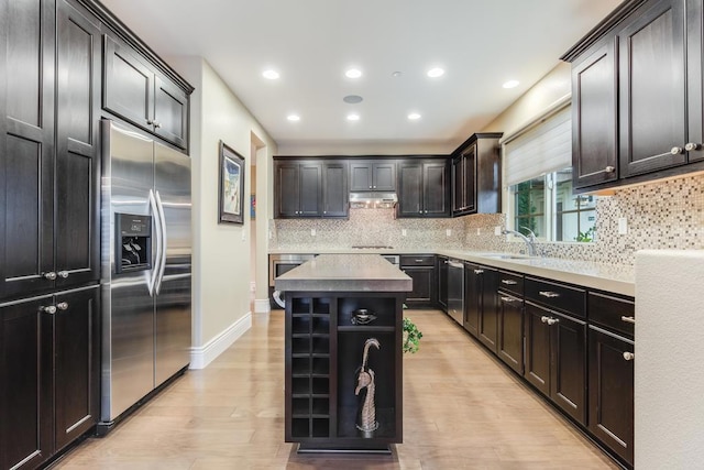 kitchen featuring appliances with stainless steel finishes, dark brown cabinetry, sink, light hardwood / wood-style floors, and a kitchen island