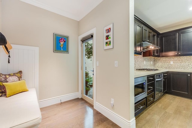 kitchen featuring light wood-type flooring, backsplash, stainless steel appliances, and ornamental molding