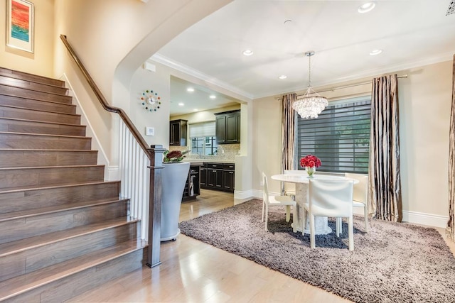 dining space featuring a notable chandelier, light hardwood / wood-style floors, and ornamental molding