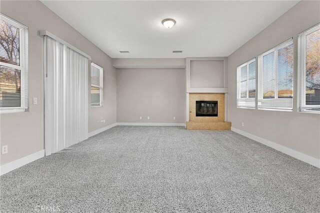 unfurnished living room featuring a tile fireplace and carpet