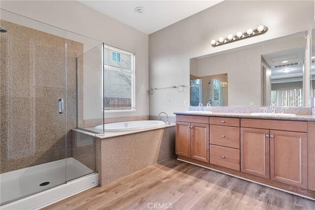 bathroom featuring vanity, a wealth of natural light, plus walk in shower, and wood-type flooring