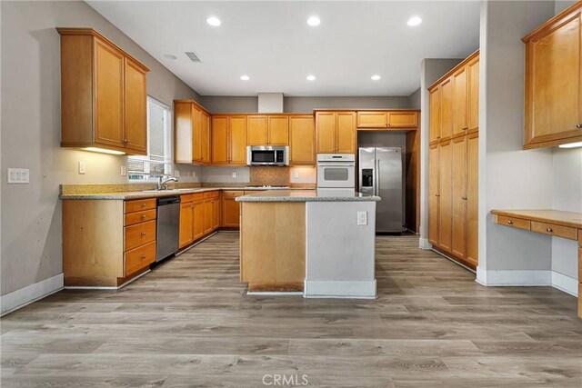 kitchen with sink, a center island, stainless steel appliances, and light hardwood / wood-style flooring