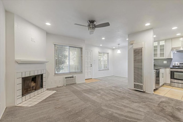 carpeted living room with a tile fireplace, a wall mounted AC, and ceiling fan