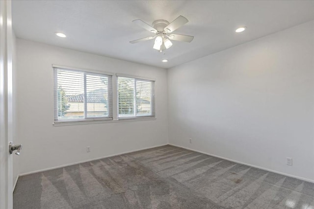 spare room featuring a wealth of natural light, ceiling fan, and dark carpet