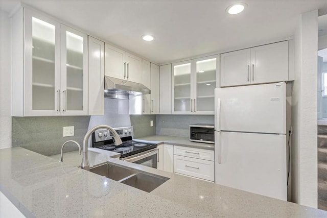 kitchen featuring white fridge, white cabinets, light stone counters, and stainless steel range with electric stovetop