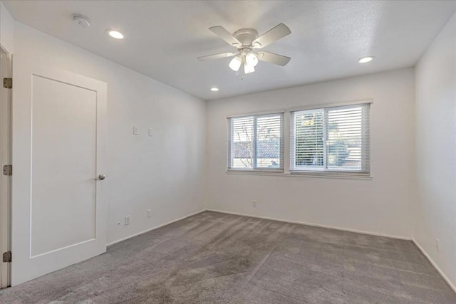 empty room featuring ceiling fan and dark carpet