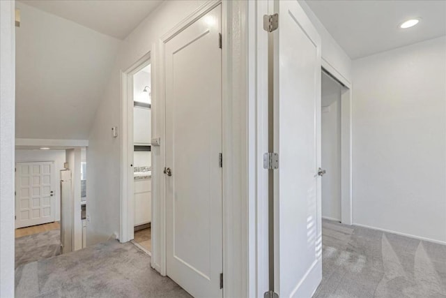 hall with vaulted ceiling and light carpet