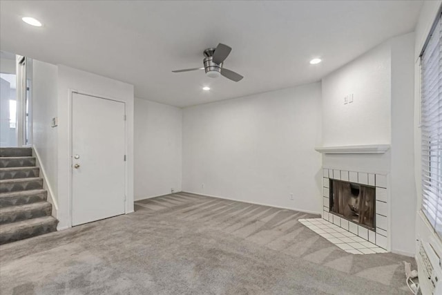 unfurnished living room featuring a fireplace, ceiling fan, and light carpet