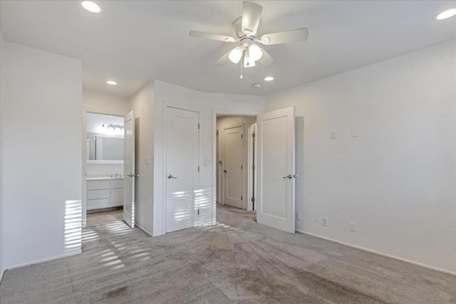 unfurnished bedroom featuring ceiling fan, ensuite bathroom, and light carpet