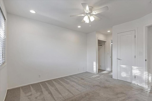 unfurnished bedroom featuring ceiling fan, multiple windows, and light carpet