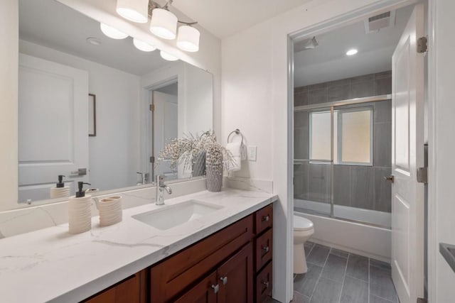 full bathroom featuring combined bath / shower with glass door, vanity, and toilet