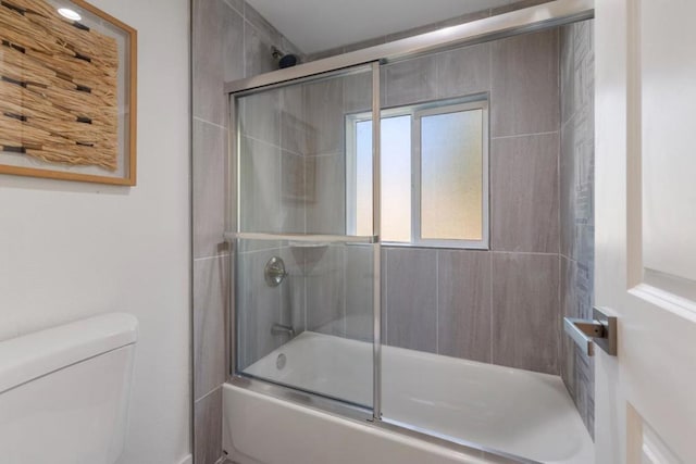 bathroom with toilet and combined bath / shower with glass door