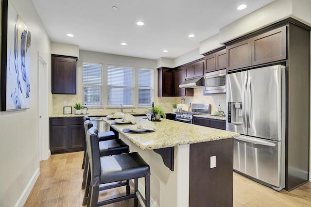 kitchen featuring dark brown cabinets, stainless steel appliances, a kitchen island, and light hardwood / wood-style floors