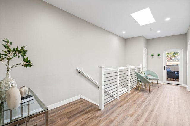 corridor with light hardwood / wood-style flooring and a skylight