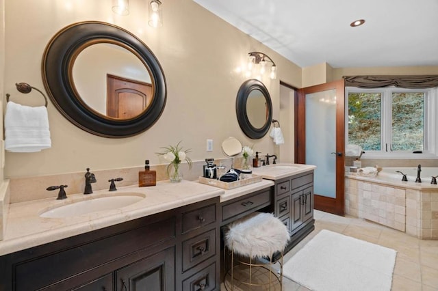 bathroom with tile patterned flooring, a relaxing tiled tub, and vanity