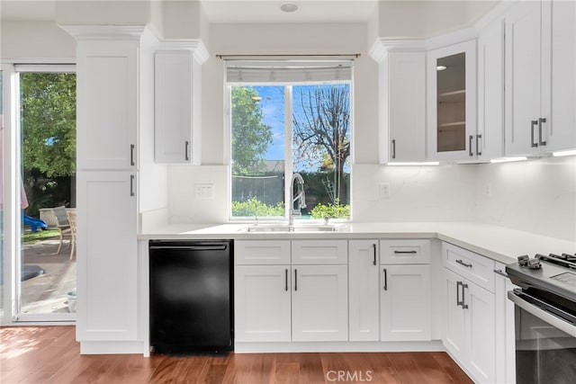 kitchen with gas stove, decorative backsplash, wood-type flooring, sink, and white cabinetry